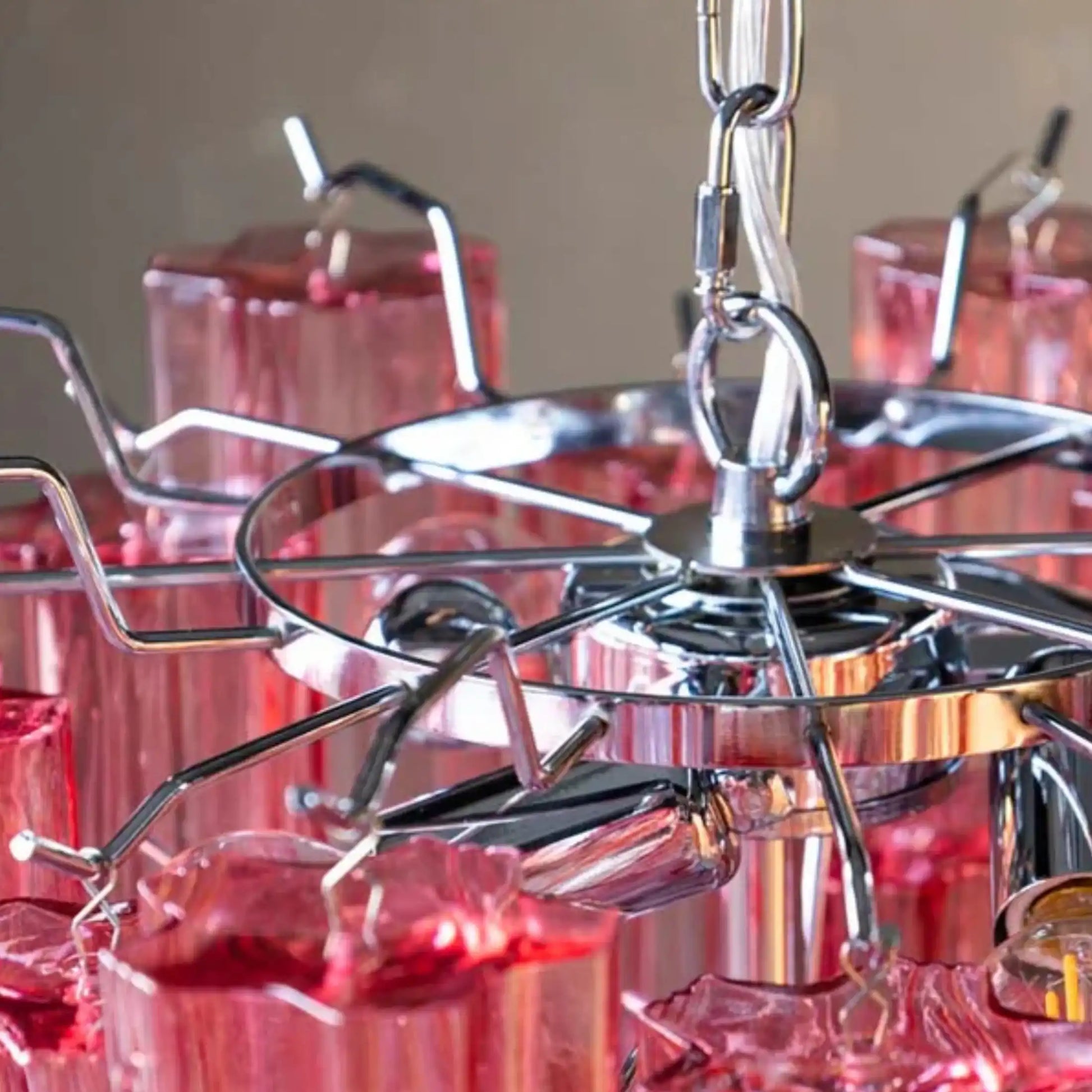 Close-up of a metallic chandelier with red glass shades against a neutral background