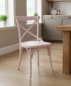 Pink chair in a kitchen setting with wooden table and cabinets.