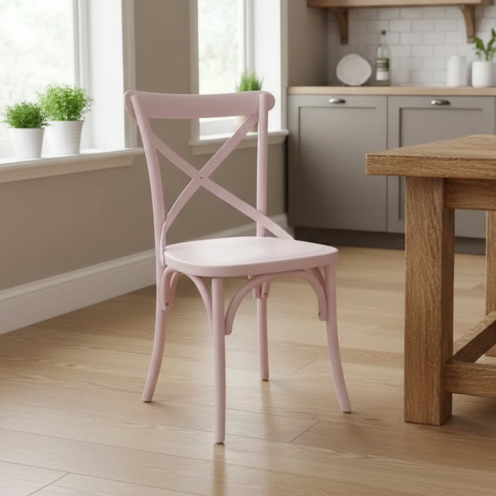 Pink chair in a kitchen setting with wooden table and cabinets.