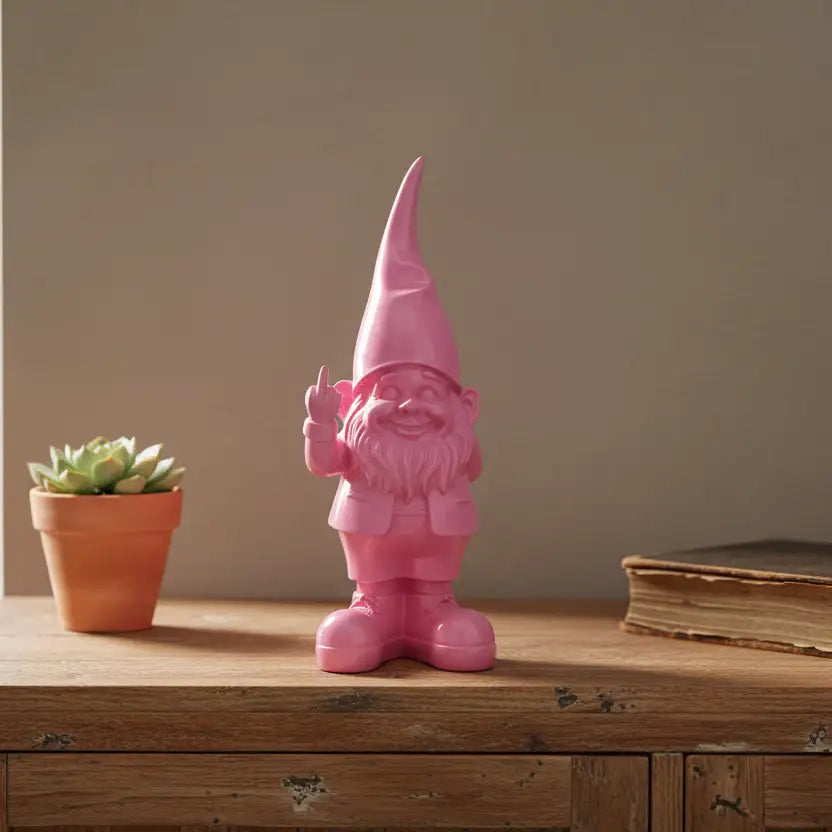 Pink gnome figurine on a wooden surface with a potted plant and book in the background.