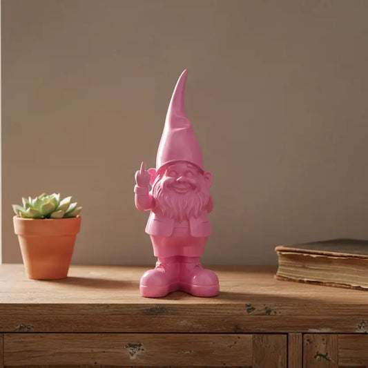 Pink gnome figurine on a wooden surface with a potted plant and book in the background.