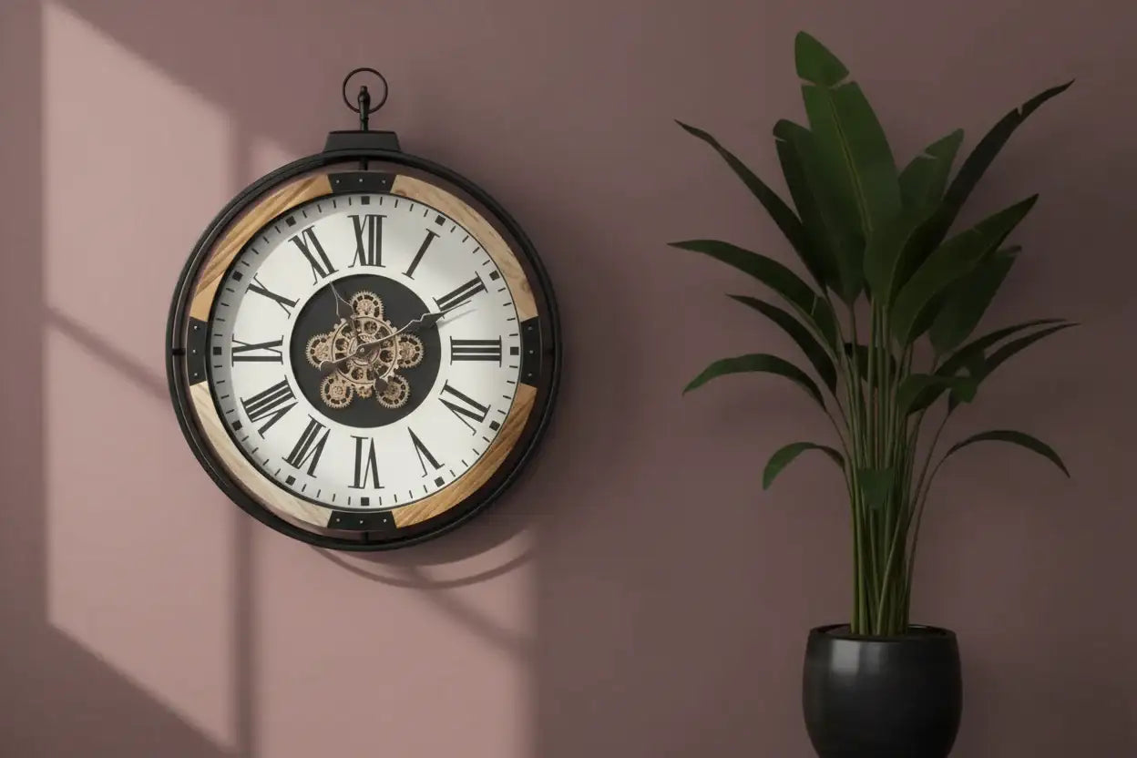 Decorative wall clock with Roman numerals on a pink wall next to a potted plant.