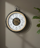 Decorative wall clock with intricate design on a beige wall next to a plant