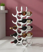 White wine rack holding multiple bottles against a pink wall.
