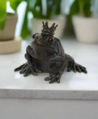 Bronze frog figurine with a crown on a white background