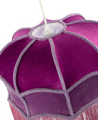 A close-up of a purple fabric chandelier shade with scalloped panels, decorative silver-gray fringe trim, and pink fringe hanging from the bottom, shown against a white background.