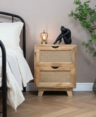 Wooden nightstand with two drawers next to a bed in a bedroom setting.