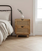 Wooden nightstand next to a bed with a vase on top in a bedroom setting.