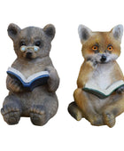 Two animal figurines, a bear and a fox, reading books on a wooden surface.