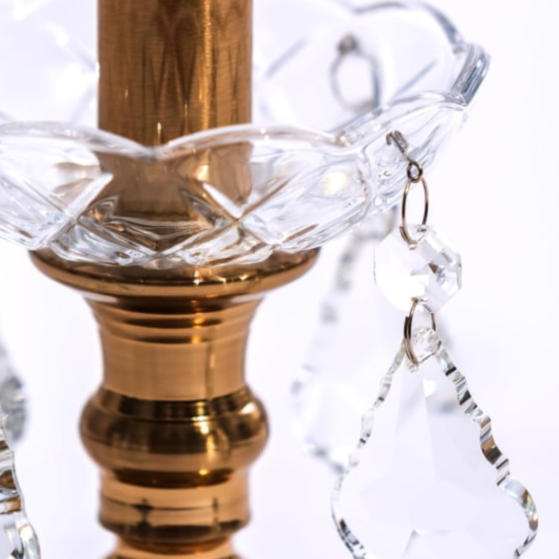 Close-up of a decorative lamp finial with gold and crystal elements on a white background