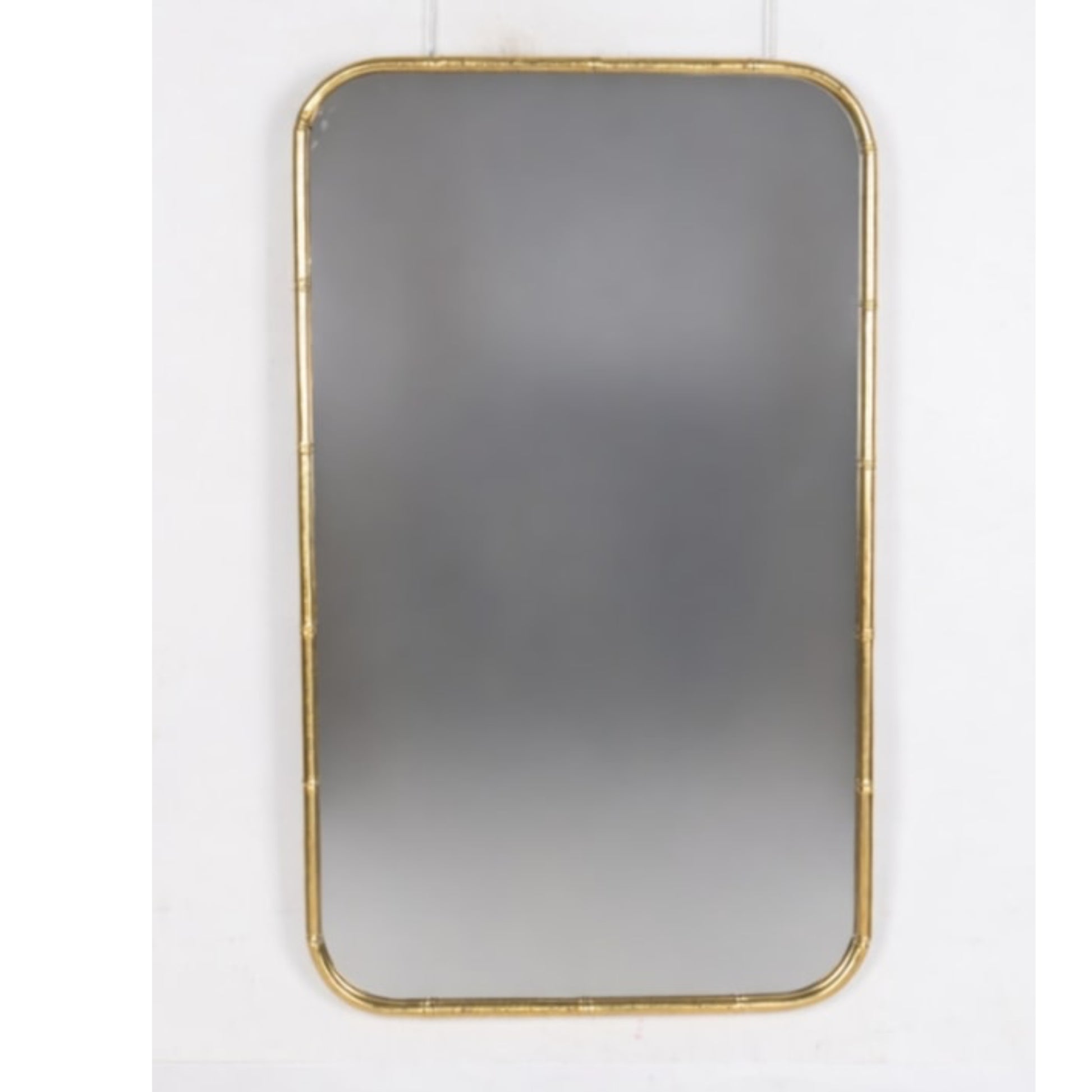 Rectangular mirror with gold frame on a white wall