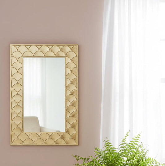 Decorative mirror with geometric pattern on a wall with a potted plant below.