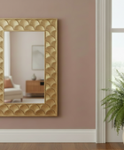Gold decorative mirror on a wall with a plant in the foreground