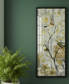 Framed artwork of birds on branches with flowers on a green wall next to a potted plant.