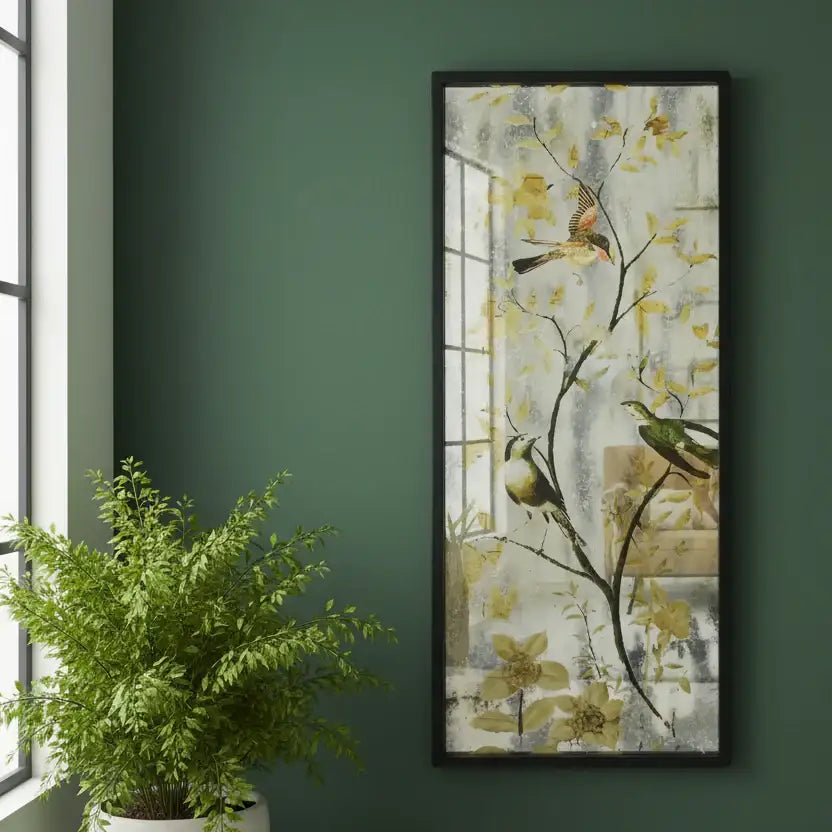 Framed artwork of birds on branches with flowers on a green wall next to a potted plant.