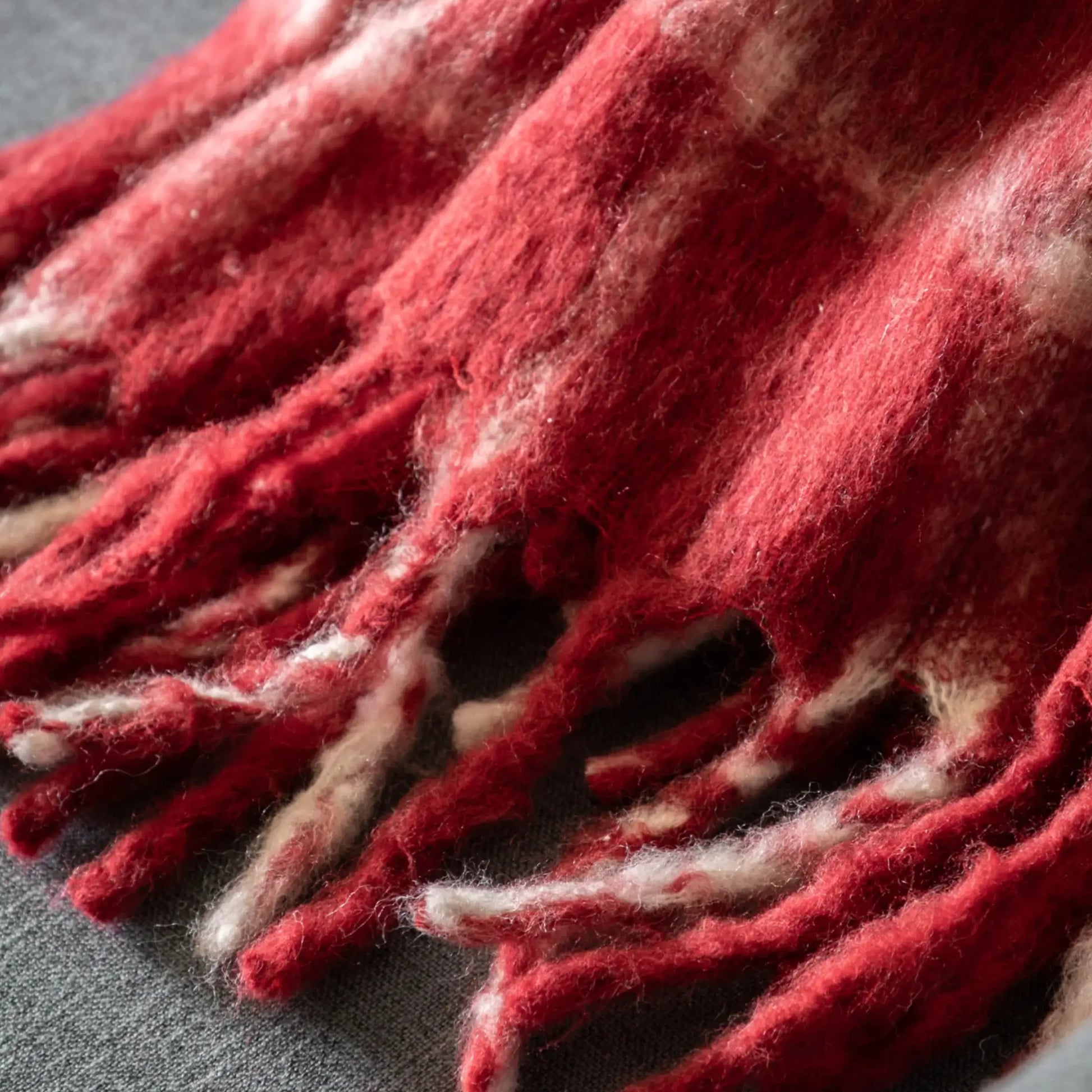 Close-up of a red and white textured fabric with fringes on a dark background