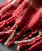 Close-up of a red and white textured fabric with fringes on a dark background