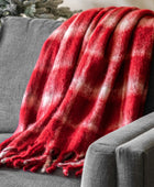 Red plaid blanket draped over a gray sofa with a Christmas tree in the background