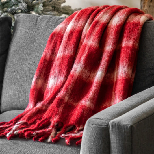 Red plaid blanket draped over a gray sofa with a Christmas tree in the background