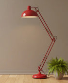 Red floor lamp with a plant on a wooden floor against a beige wall