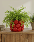 Decorative plant pot with red heart design on a wooden surface