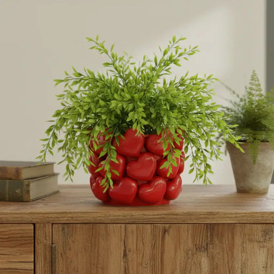 Decorative plant pot with red heart design on a wooden surface