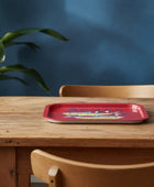 Red tray on a wooden table with a plant and blue wall in the background