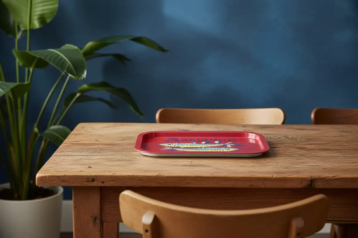 Red tray on a wooden table with a plant and blue wall in the background