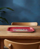 Red tray with colorful design on a wooden table against a blue wall