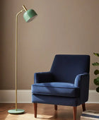 Blue armchair with a green floor lamp against a beige wall