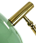 Close-up of a green glass object with a gold metal handle on a white background