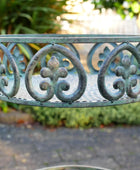 Decorative metal garden bench with intricate designs in a garden setting