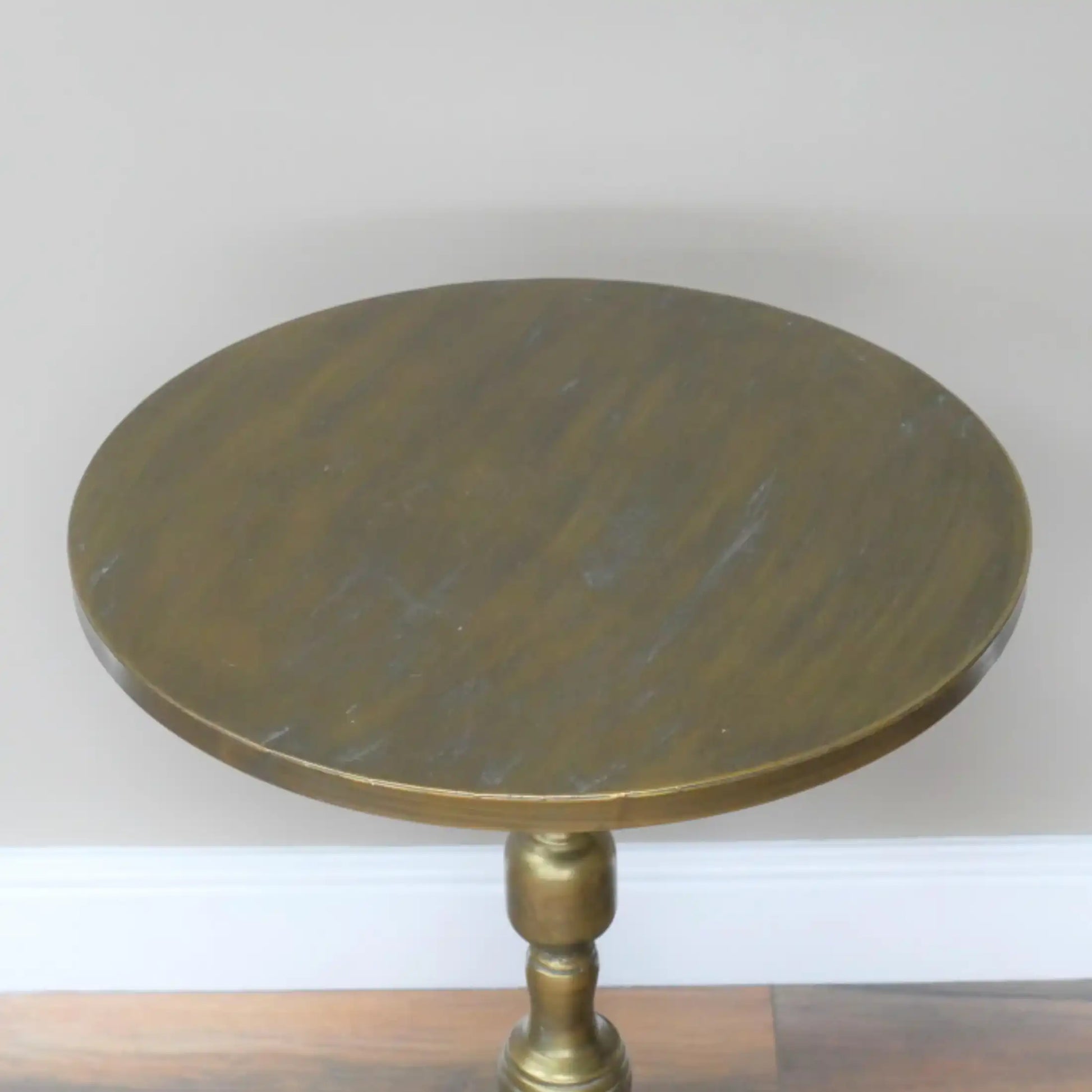 Round wooden table with a brass pedestal base on a plain background
