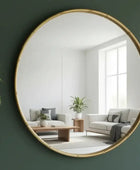 Round mirror with gold frame reflecting a living room with a sofa and coffee table.
