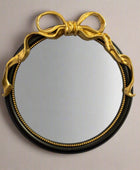 Round mirror with gold bow frame on a beige background