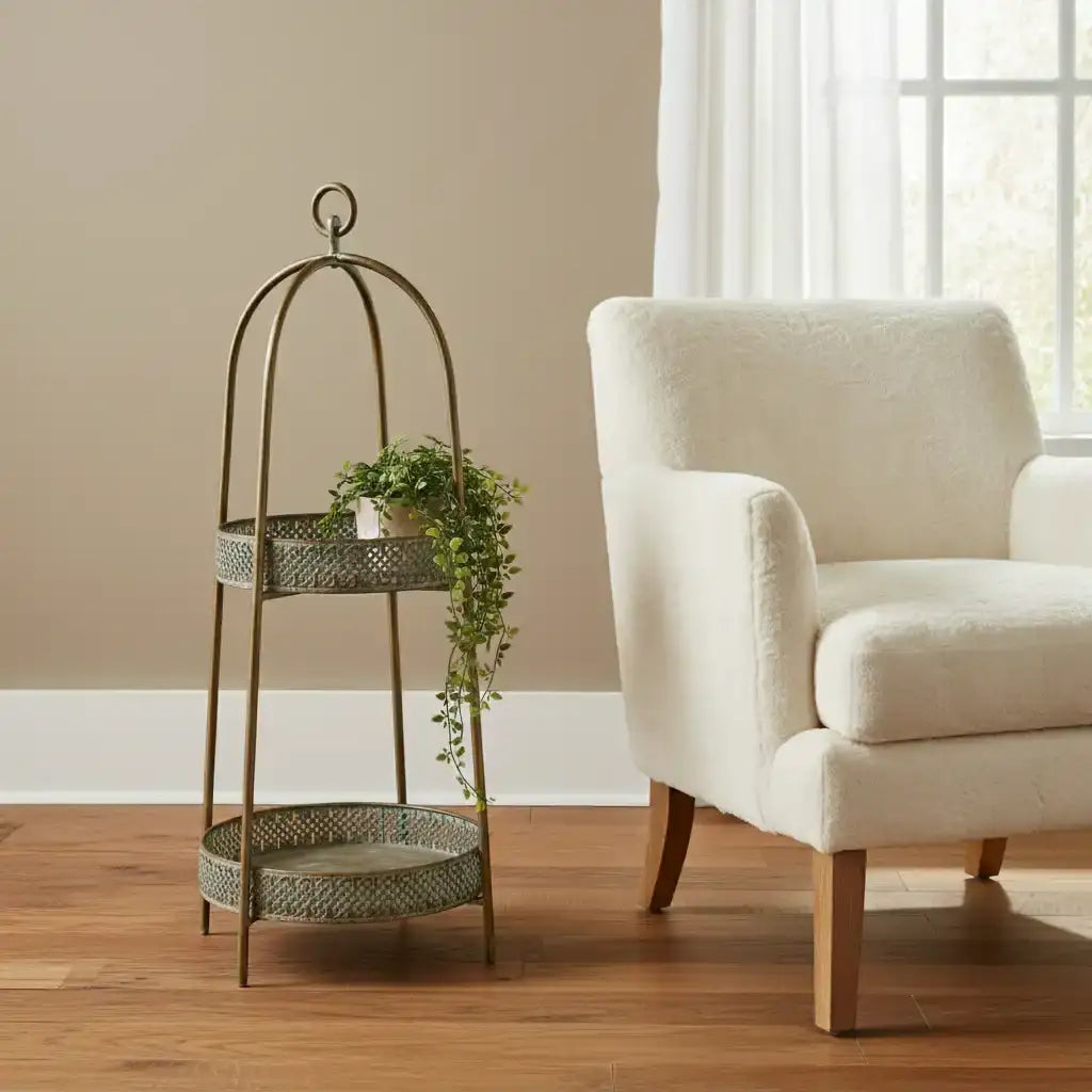 Decorative metal plant stand with a plant next to a beige armchair in a room with a window.