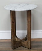 Small round table with marble top and wooden base against a plain wall.