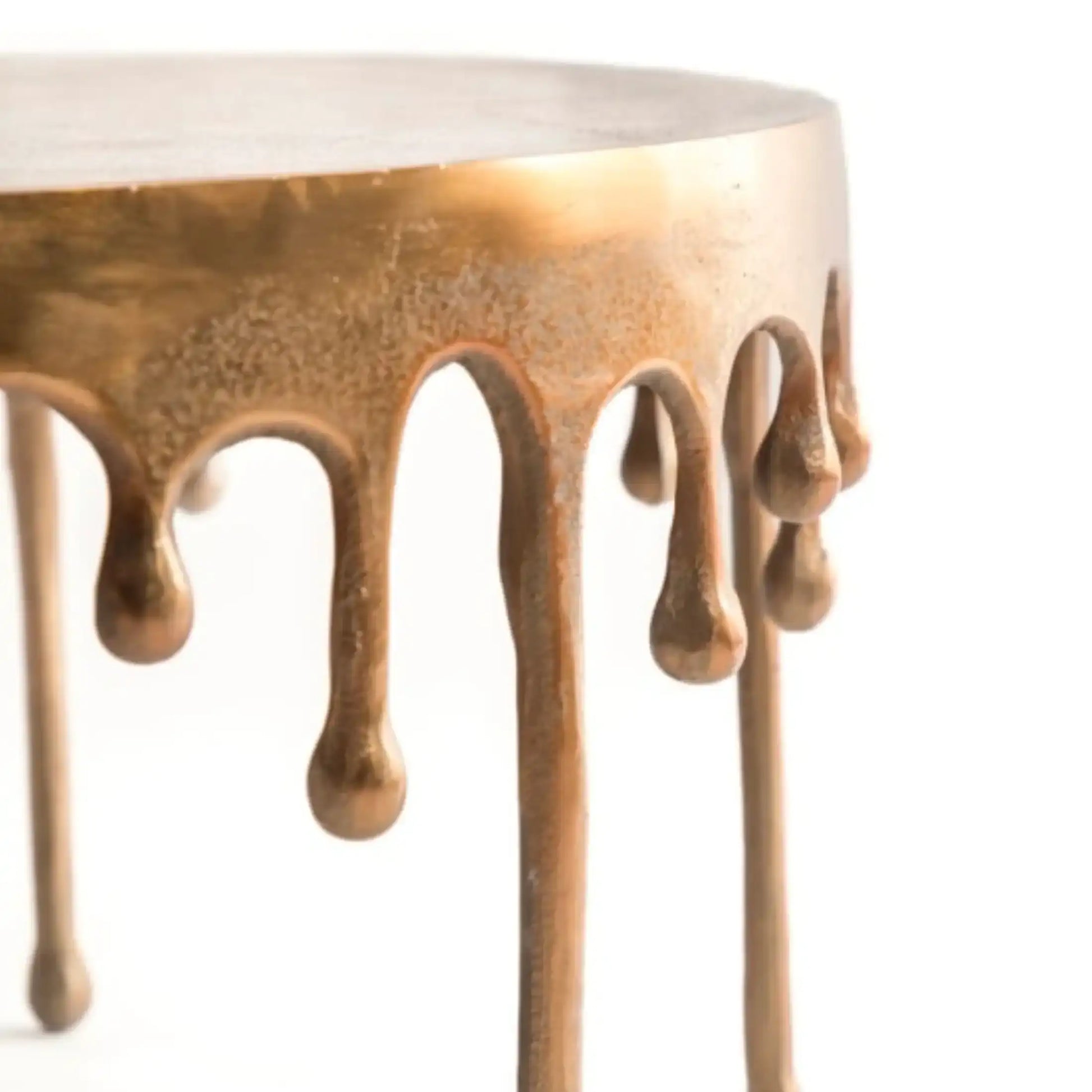 Table with bronze-colored metal drips on a white background