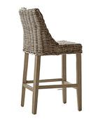 Wicker bar stool in a room with white walls and a window.