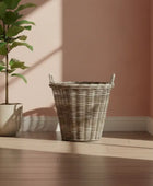 Wicker basket and potted plant on a wooden surface with a pink wall background