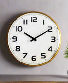 Round wall clock with gold frame on a plain wall