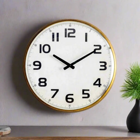 Round wall clock with gold frame on a plain wall