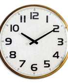 Round wall clock with gold frame and white face on a white background