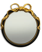 Round mirror with gold decorative bow and black frame on a white background