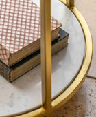 Two books stacked on a round marble table with a gold frame.