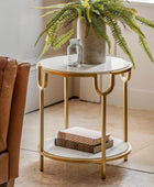 Small round marble table with gold frame next to a brown leather chair, with a plant in the background.