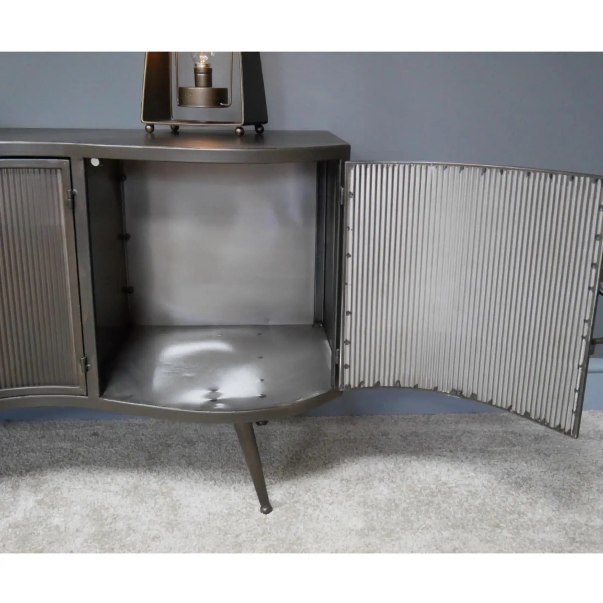 Metallic sideboard with corrugated metal doors on a gray carpeted floor.