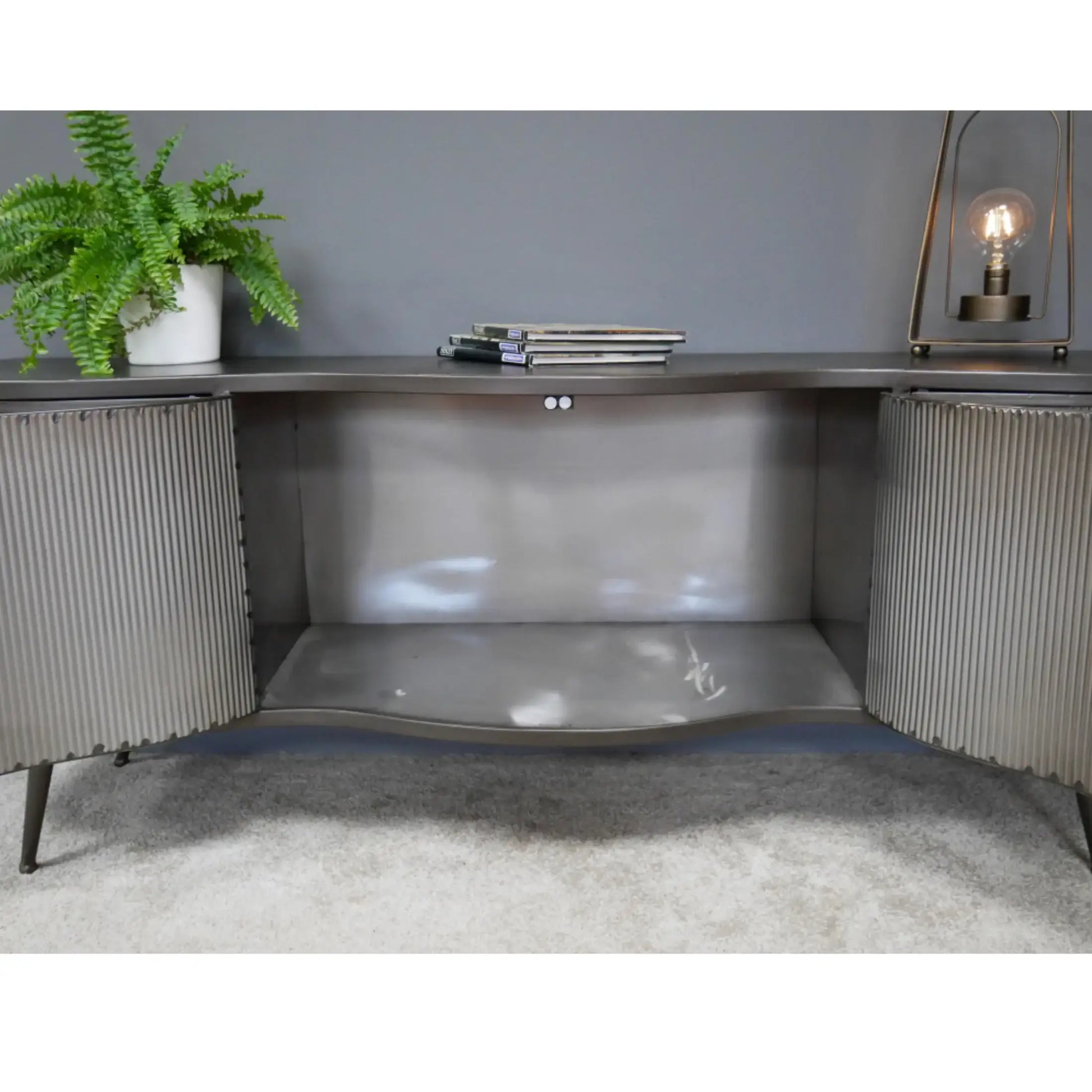 Modern corner desk with a plant, lamp, and books in a room with gray walls and carpet.
