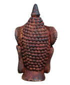 Rust-colored Buddha statue against a stone wall background