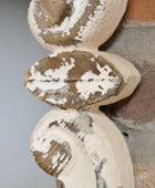 Decorative wooden finial with peeling paint on a neutral background